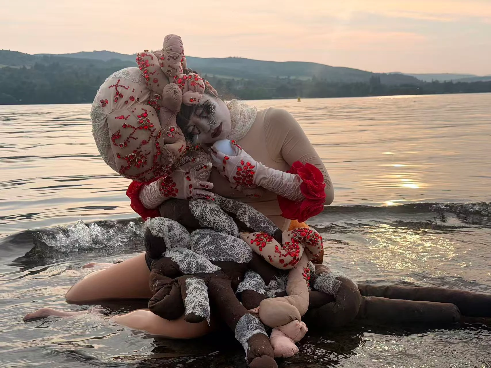 A Slice of the Crow: a performer embracing soft sculptural forms in a lake at sunset